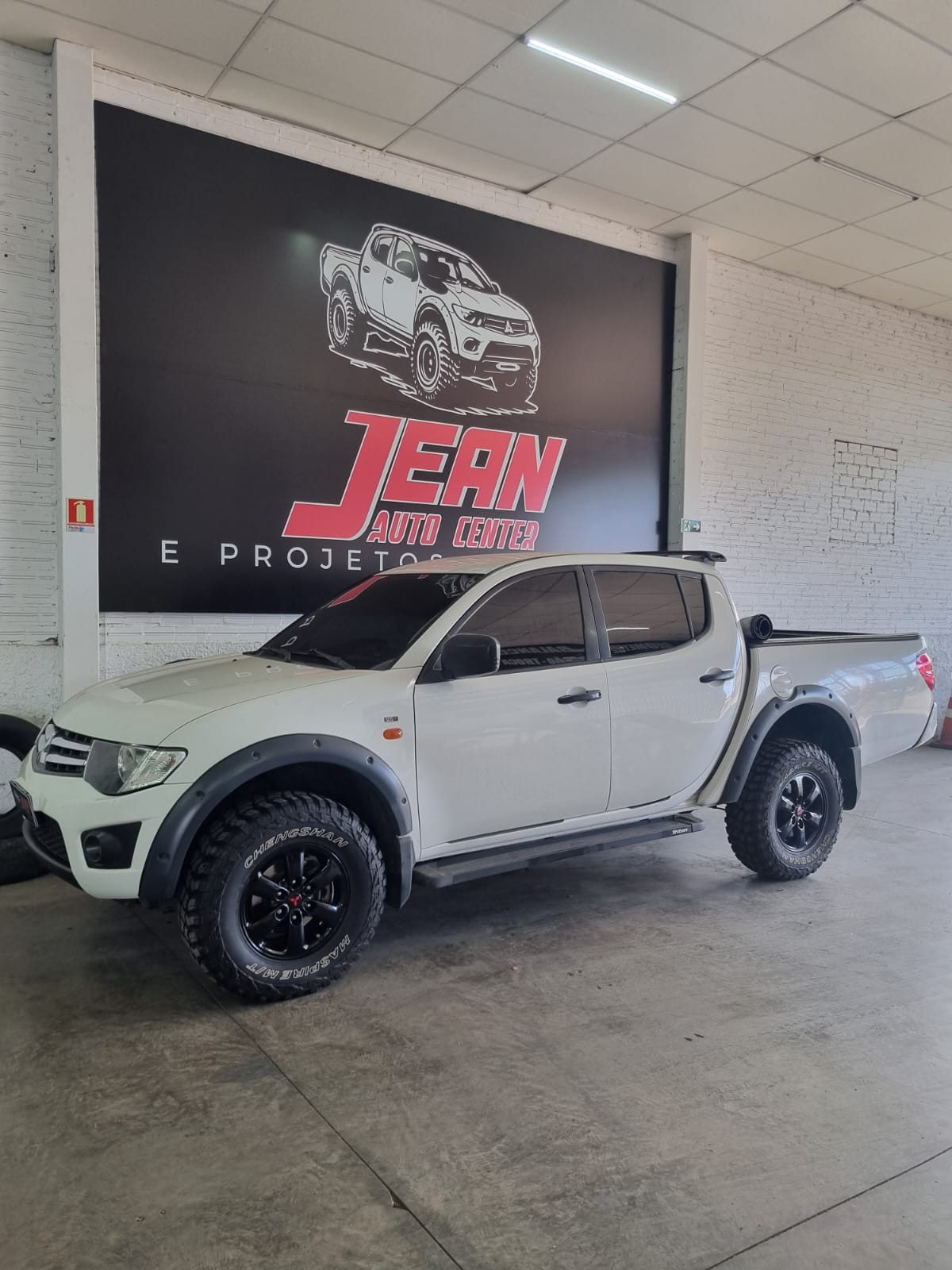 Mitsubishi L200 Triton branca com para-lama alargado, snorkel e pneus off-road
