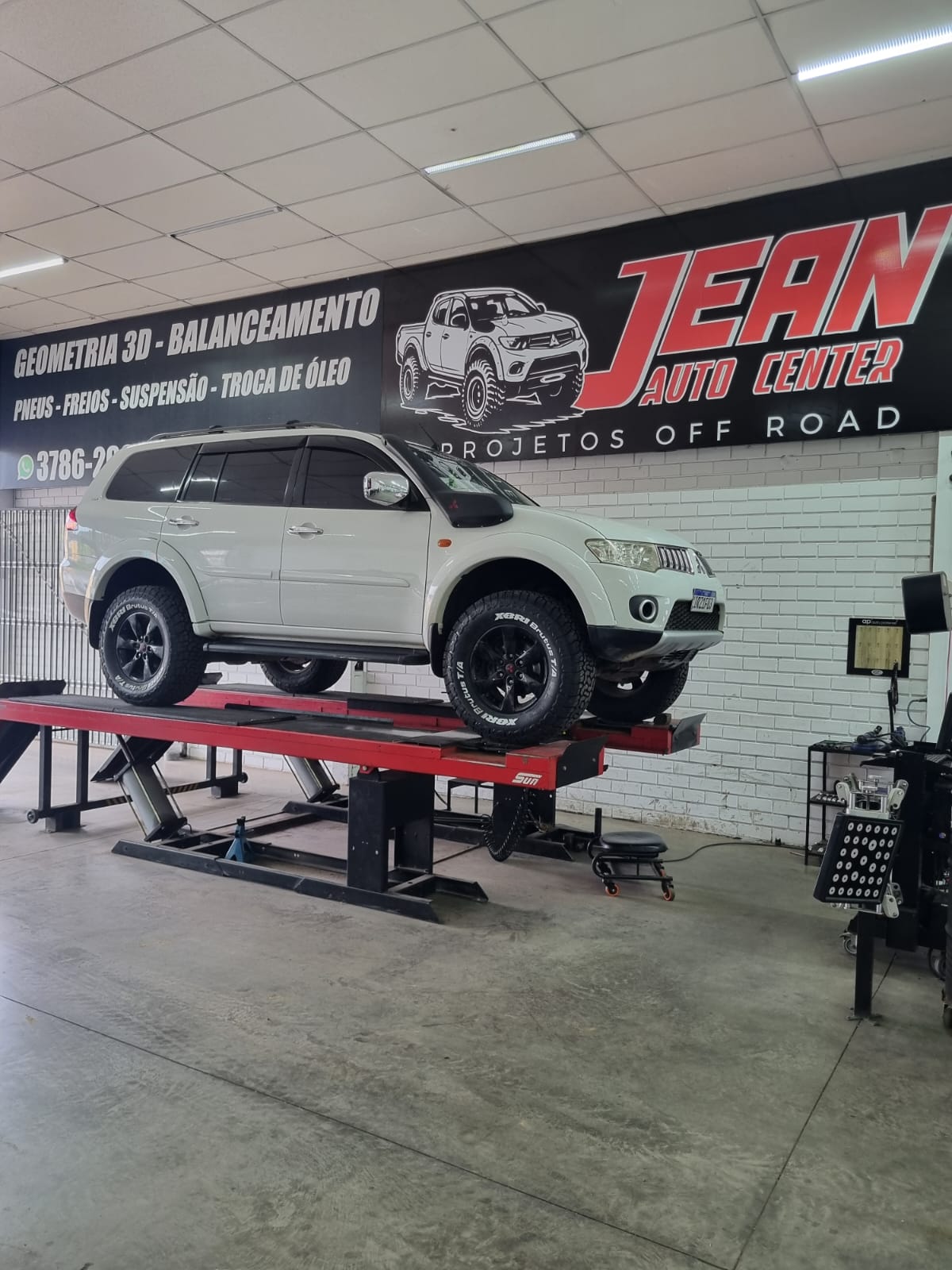 Mitsubishi Pajero Sport branco elevado no alinhador de geometria 3D